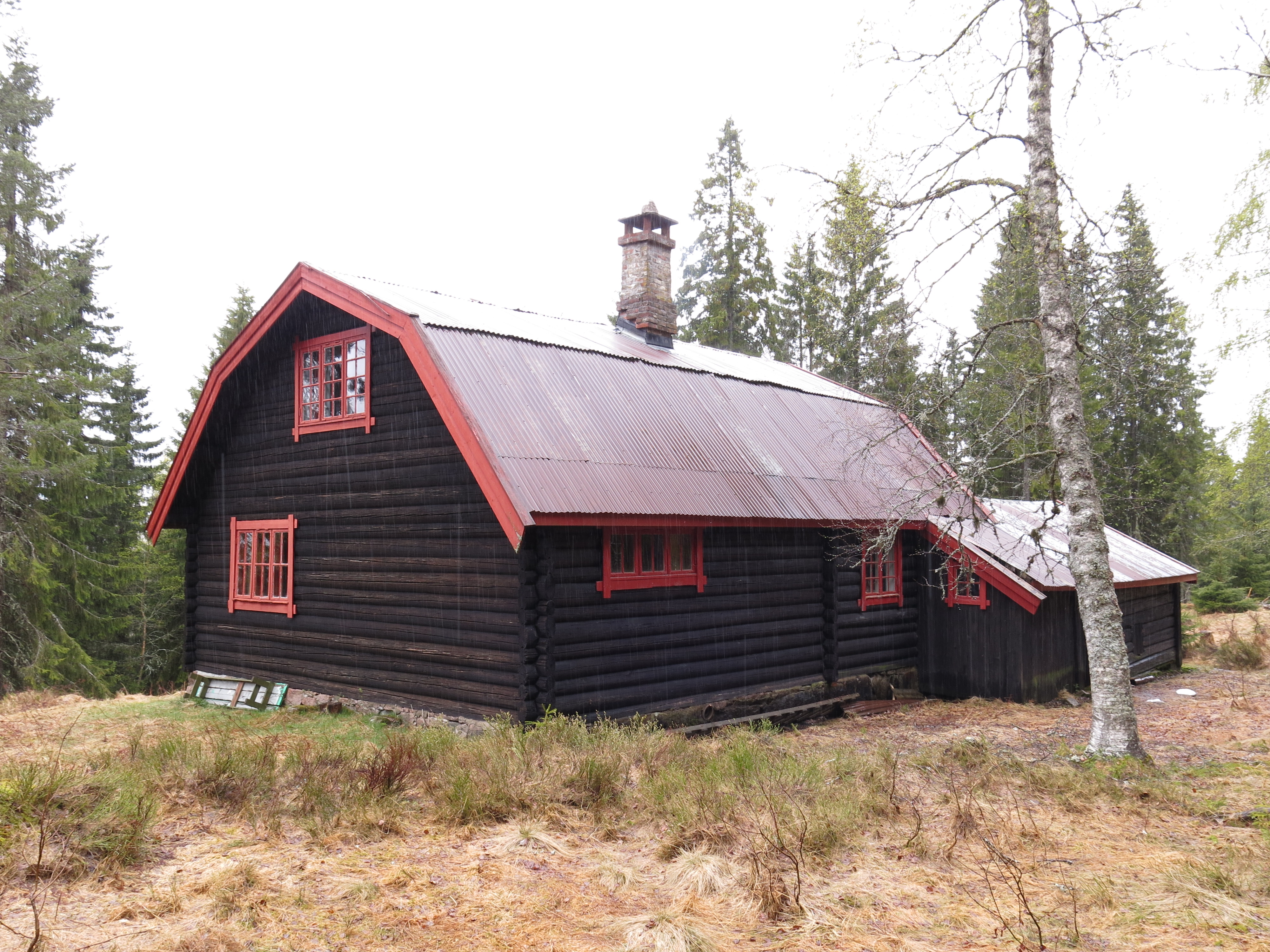 Bilde av hytta på Rudsæter. Det er en toetasjes laftet tømmerbygning med smårutede vinduer, mansardtak i blikk og åpen sval. Foto: Ingeborg Magerøy, Riksantikvaren