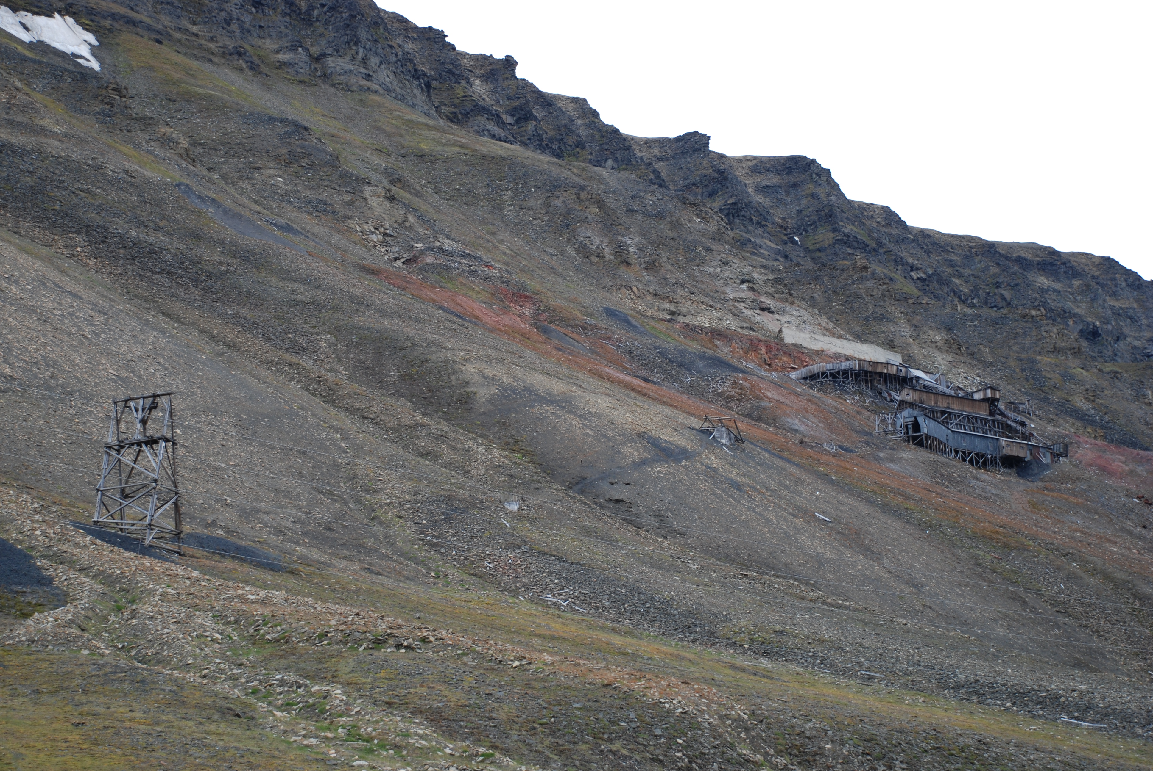 De ikoniske rekkene med taubanebukker på Longyearbyens fjellsider er svært utsatt for utglidning i bakken ettersom permafrosten tiner samt for stein- og snøras. I denne rekken til Gruve 2 er to av bukkene tatt av et snøras fra fjelltoppen. Foto: Susan Barr / Riksantikvaren
