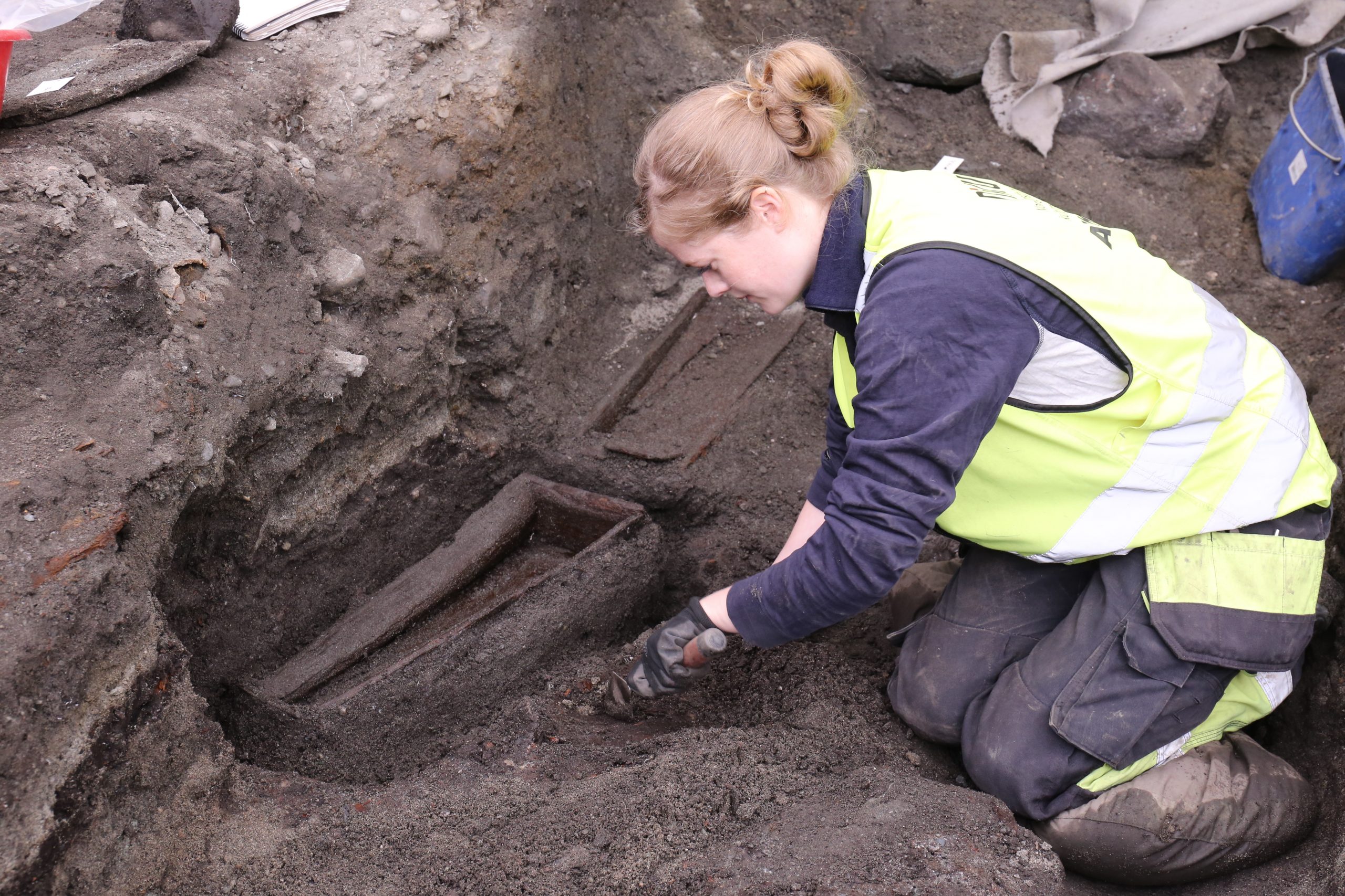 Bilde av Arkeolog Karen Ørbog Oftedal, NIKU, graver ut barnekister fra kirke 3. Foto: Anna K. Wändahl, NIKU