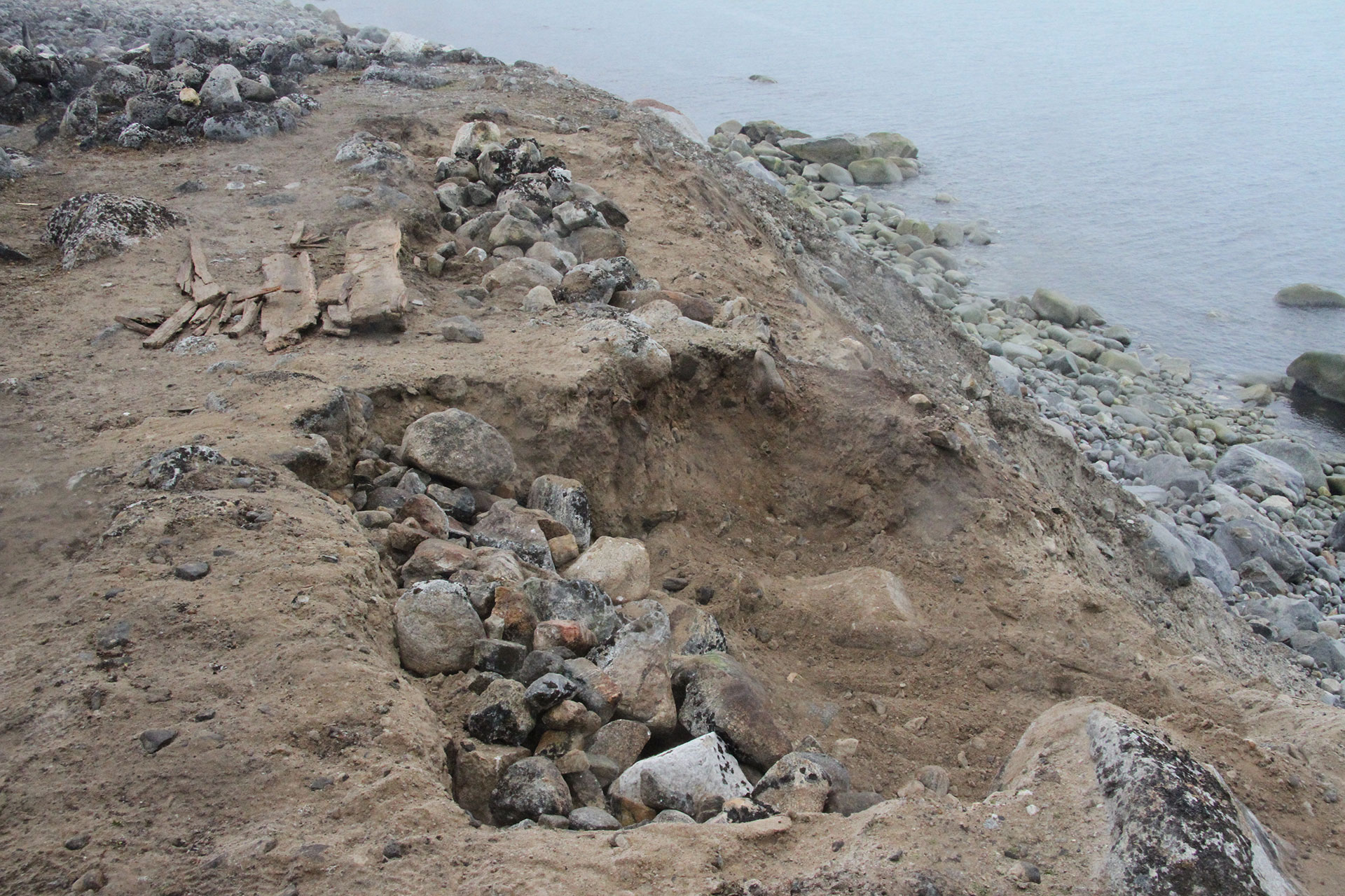 Bilde av tre hvalfangergraver på Likneset var nesten rast i havet på grunn av erosjon. Her er en av gravene, med kiste, fjernet av arkeologene. Foto: Siri Wolland, Riksantikvaren