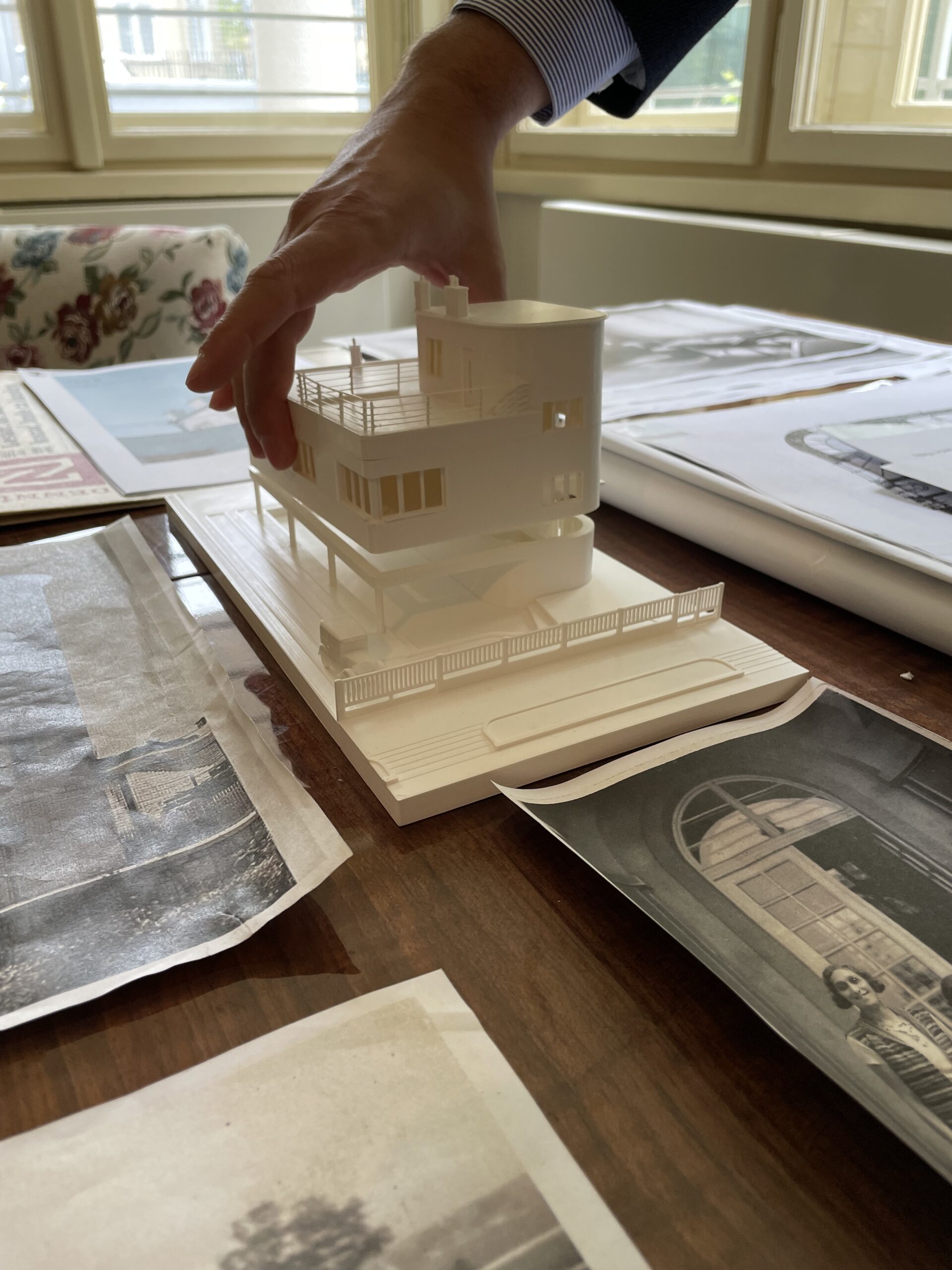 En modell av en funksjonalistisk villa står på et bord omringet foto og avisutklipp.
