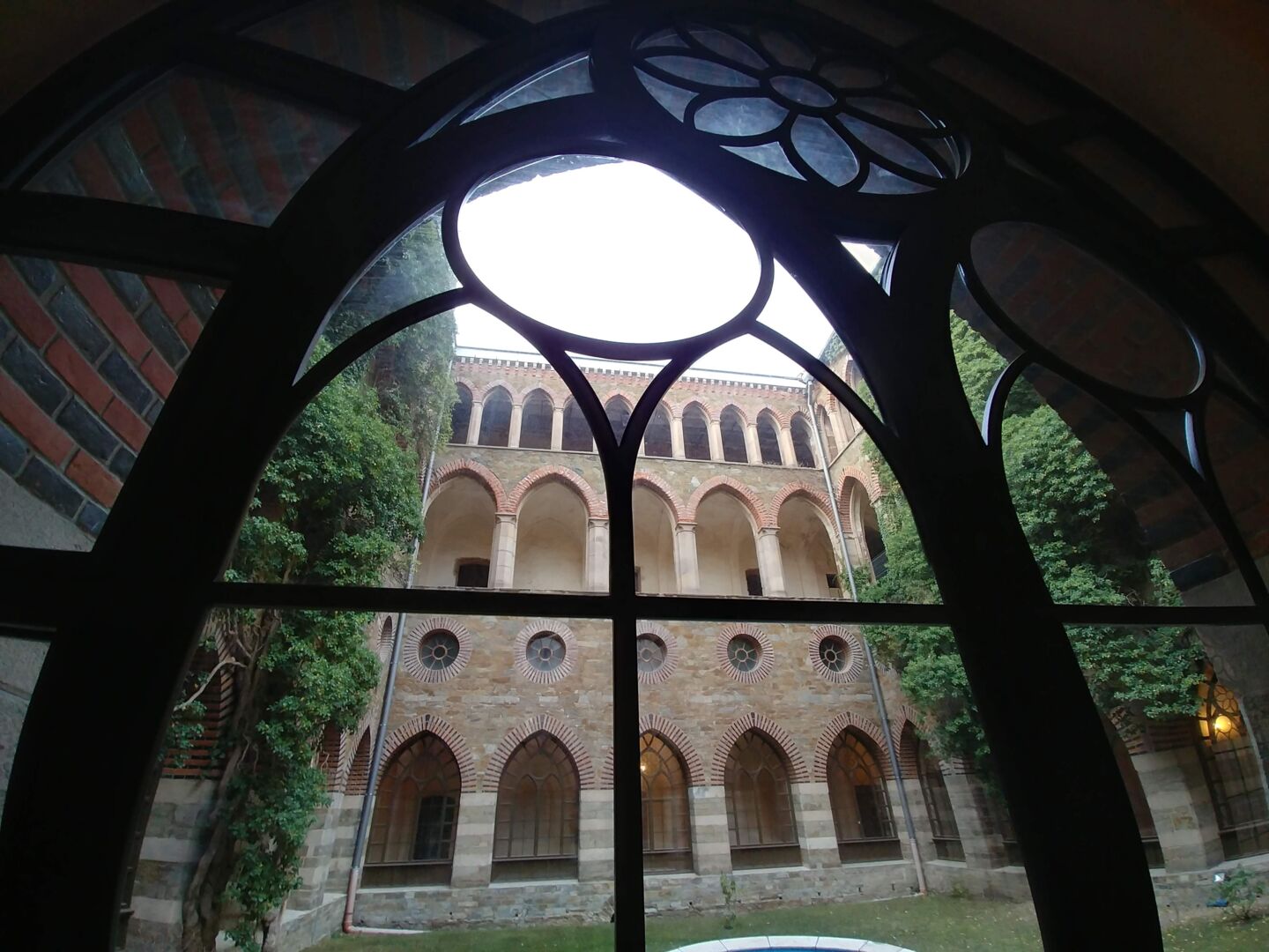 Bildet er tatt fra innsiden av et gotisk vindu og ser ut på borggården i Marianne av Oraniens palass med grønn eføy langs veggene.