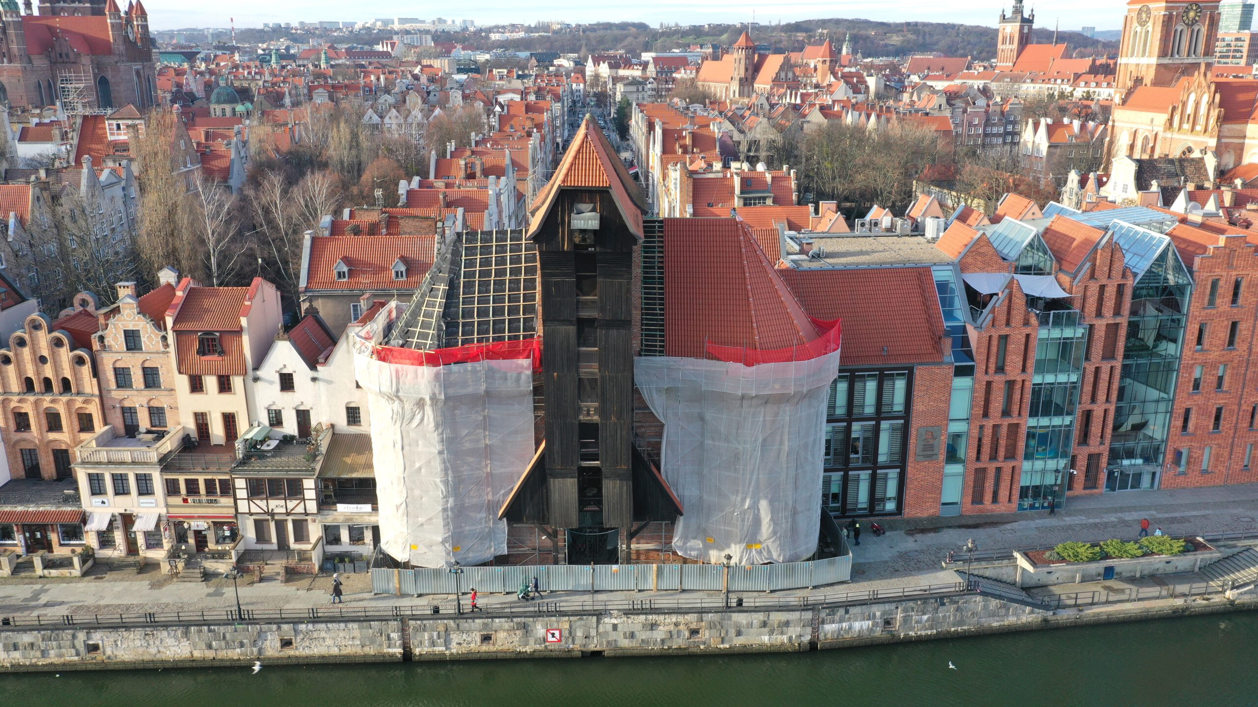 Oversiktsbilde over havneanlegget i Gdansk med det historiske krananlegget i midten, her dekket til med plast for renovering.