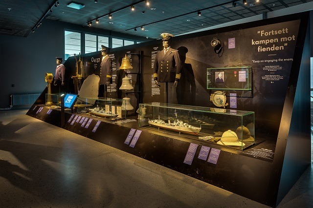 Bilde fra en norsk utstilling om motstandskampen, med uniformer, gjenstander og informasjonstekster.