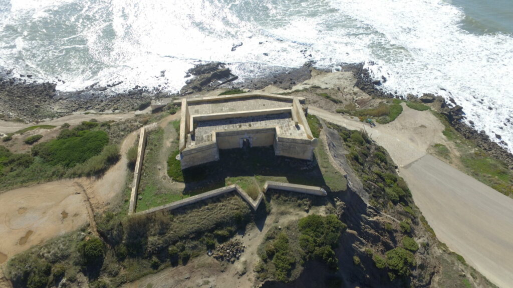 Et fort beliggende ved kysten med bølger som slår opp.