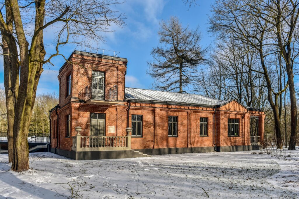En rektangulær bygning i rustrød murstein, med et to-etasjers tårn på venstre side, beliggende i vinterlandskap med lett snødryss på bakken.