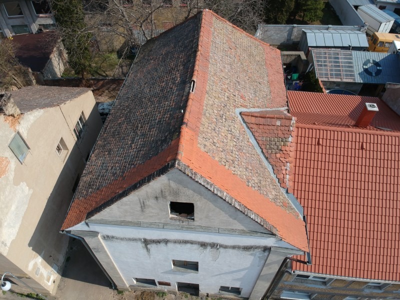 Bildet sett fra fugleperspektiv av en synagoge med delvis restaurert tak i rustrød farge.